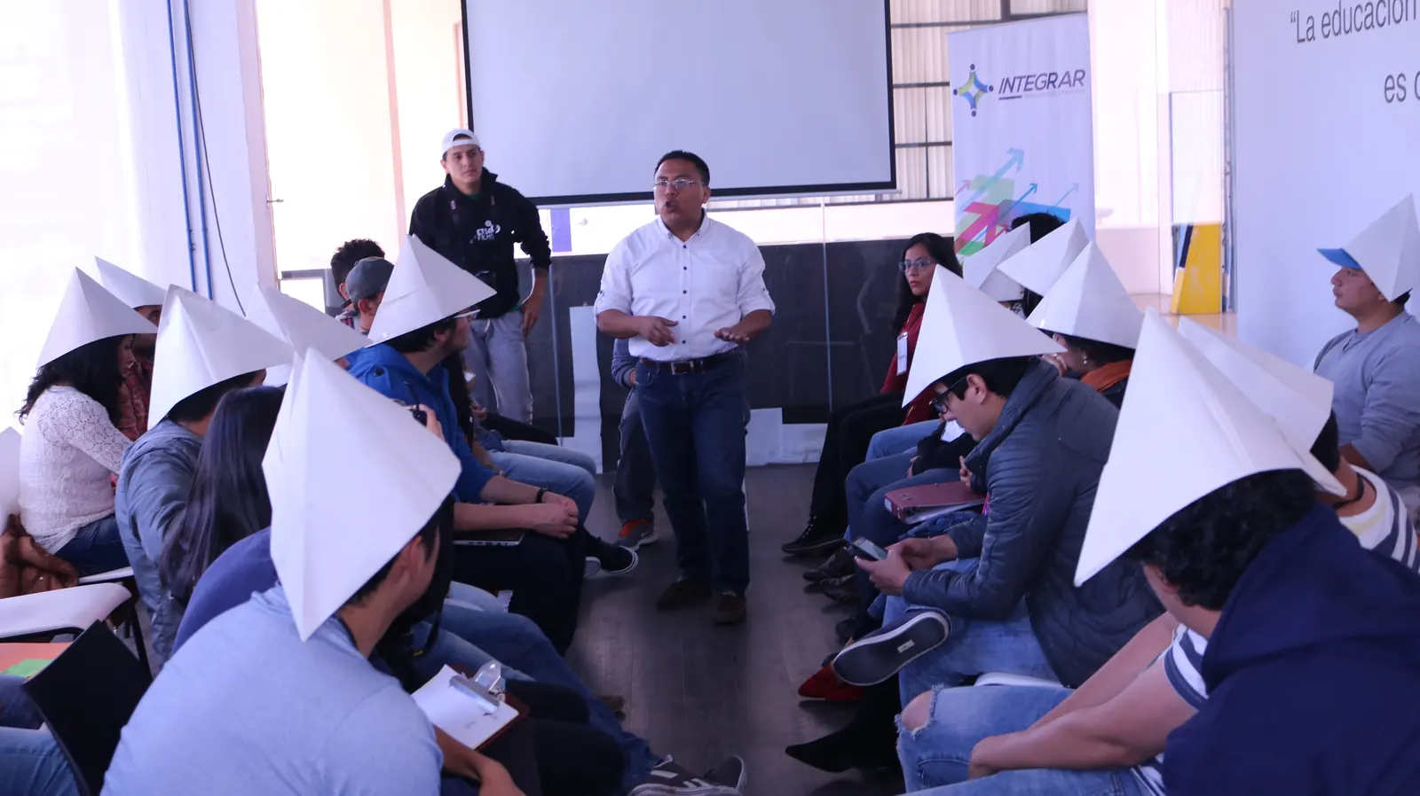 Facilitador de Integrar guiando una dinámica con jóvenes que llevan sombreros de papel