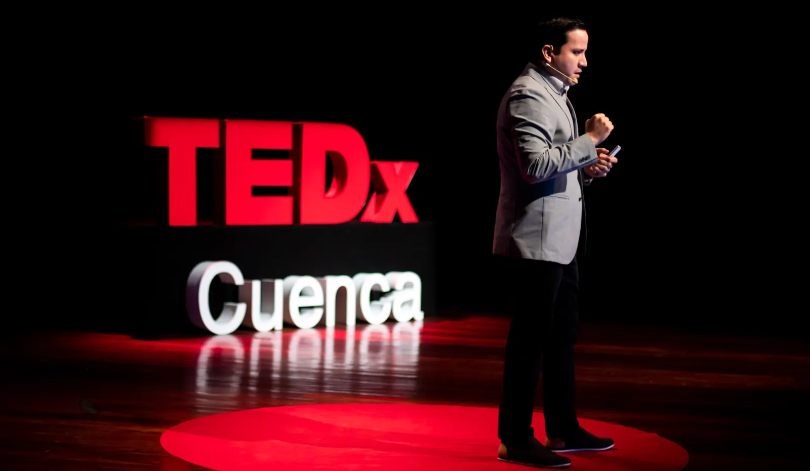 Speaker en escena en TEDxCuenca, sobre el círculo rojo junto a las letras del evento