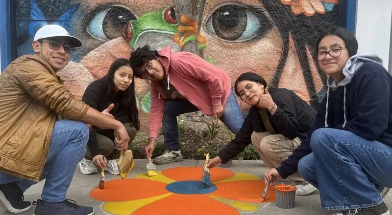 Jóvenes pintando un mural comunitario en el espacio público